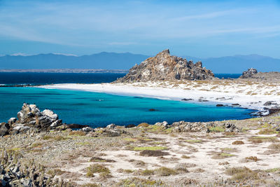 Scenic view of rock formation by sea against blue sky at isla damas island