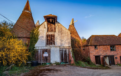 Old abandoned building by trees against sky