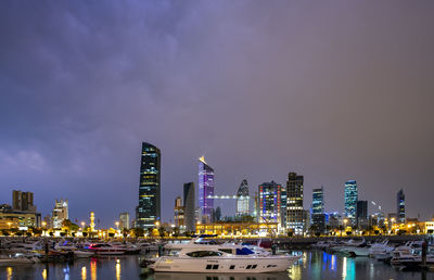 Illuminated modern buildings in city against sky at night