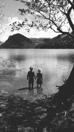 Friends standing in lake against mountains