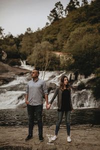 Full length portrait of young woman against trees