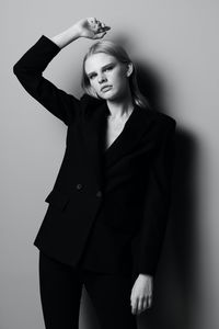 Portrait of young woman standing against black background