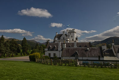 Houses on field by buildings against sky