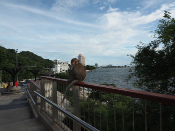 Man on bridge over river against sky in city