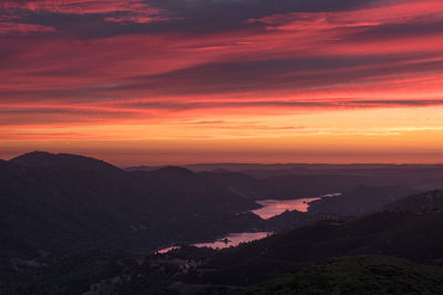 Scenic view of dramatic sky over silhouette landscape during sunset