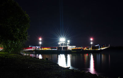 Illuminated bridge over river against sky at night