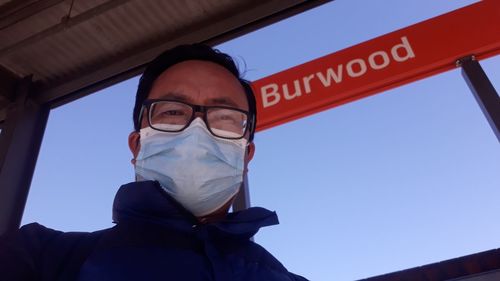 Low angle portrait of man wearing flu mask against sky