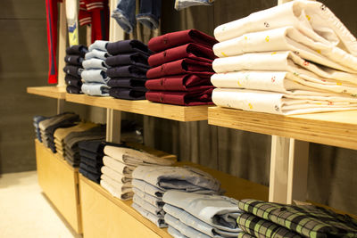 Shirts and pants hanging on hangers on a clothing rack and arranged in a shelf in a clothing store