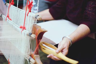 Midsection of woman weaving loom in industry