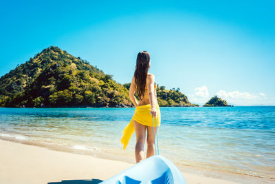 Rear view of woman with kayak standing at beach