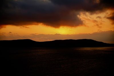 Scenic view of silhouette landscape against orange sky