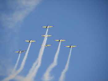 Low angle view of airshow against clear blue sky