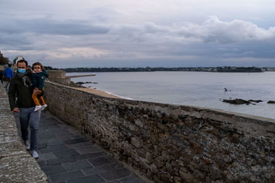 People standing on shore against sky