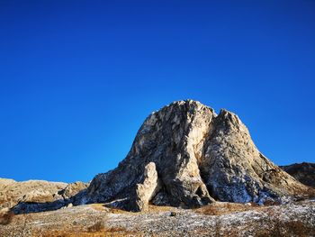 Low angle view of rock formation against clear blue sky