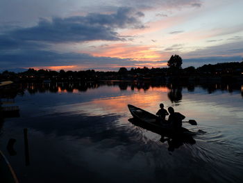 Silhouette man swimming in lake against sky during sunset