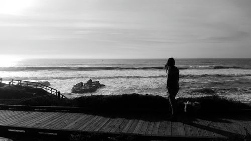 Silhouette woman on beach against sky