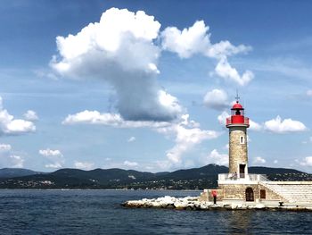 Lighthouse by sea against sky