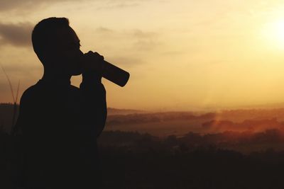 Silhouette man standing against orange sky during sunset