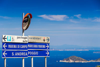 Information sign by sea against blue sky