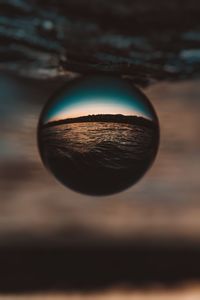 Close-up of sunglasses against sky at sunset