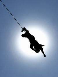 Low angle view of silhouette man jumping against sky