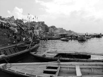 Boats moored at harbor against sky in city