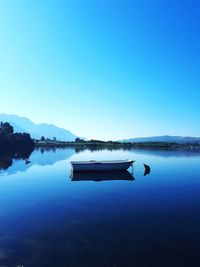 Scenic view of lake against clear blue sky