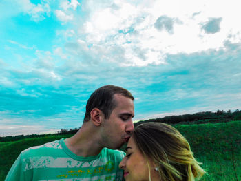 Close-up of young couple against blue sky