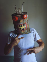 Midsection of person holding mask against wall