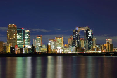 Illuminated cityscape by yodo river against sky at night