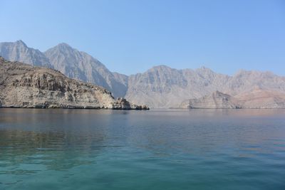 Scenic view of lake and mountains against clear blue sky