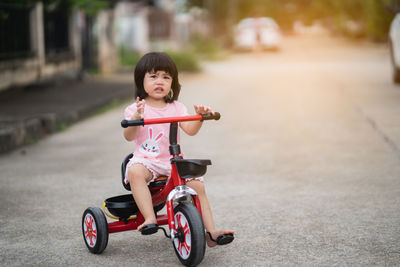 Cute girl riding bicycle on road in city