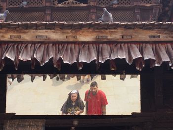 Man and woman reflecting on mirror in balcony of house