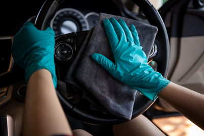 Women wearing green gloves cleaning steering wheel car with micro fiber gray cleaning car concept