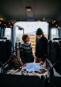 Smiling couple looking at map standing by motor home