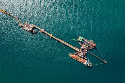 Aerial view oil pipes to oil tanker ships at pier off the coast in beautiful peaceful environment.