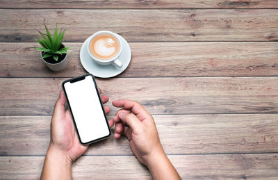 Directly above shot of hand holding coffee cup on table