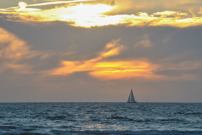 Sailboat in sea against sky during sunset