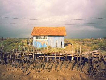 Built structure on field by houses against sky