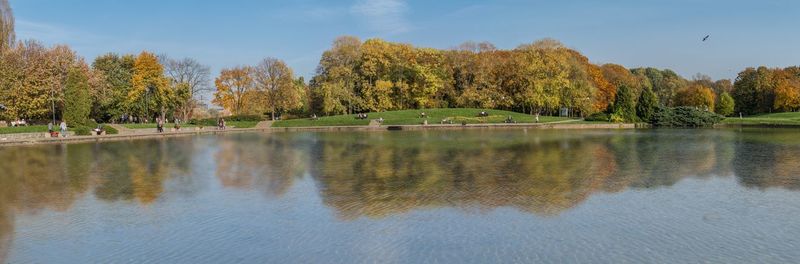 Scenic view of autumn trees by lake against sky