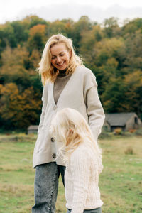 Portrait of smiling young woman with dog on field