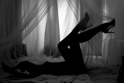 Silhouette woman in high heels lying in bed