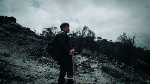 Young man standing on land against sky