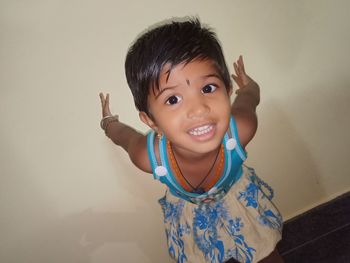 Portrait of girl standing against wall at home