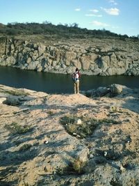 Rear view of man standing on rock by river