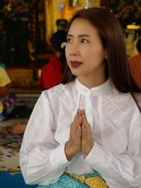 Woman with hands clasped looking away in temple