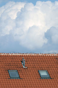 Chimneys on the roof of a house and two windows against blue sky