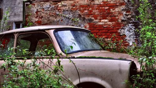 Close-up of abandoned car on brick wall