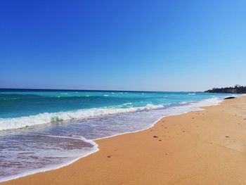 Scenic view of beach against clear blue sky