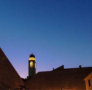 Low angle view of illuminated buildings against clear blue sky